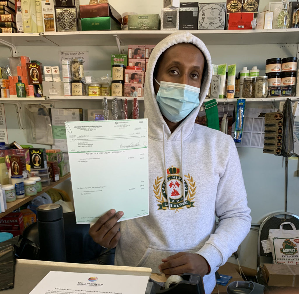 Store owner holding up gift certificate program packet
