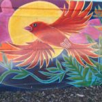 Portion of Teralta Park Unity mural featuring featuring a vibrant red bird flying in front of a sun.