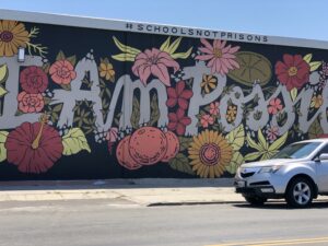 Mural featuring the words "I Am Possible" surrounded by flowers painted on the side of a building.