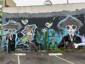 Colorful urban mural depcting mariachi skeletons.