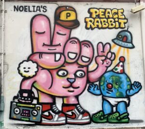 Urban wall mural depcting a cartoonish bunny making a peace sign.