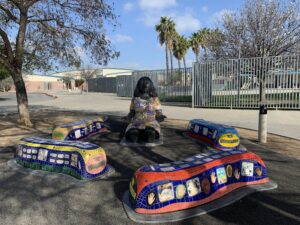 Vibrant mosaic sculpture of a woman speaking surrounded by benches at Rosa Parks Elementary school.