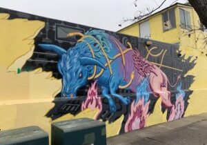 Urban mural depicting a a colorful bull jumping out of the wall.