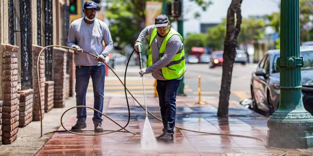 City Heights Business Association Clean & Safe crew members powerwashing the sidewalk on University Ave.