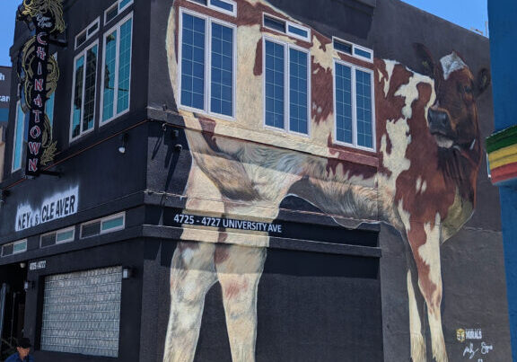 Large cow mural painted on the outside of a building.